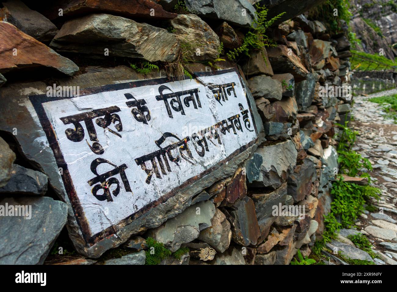 Una pietra incisa con il testo hindi che significa "non c'è conoscenza che possa essere raggiunta senza un maestro", riferita a Guru Purnima, India. Un simbolo Foto Stock