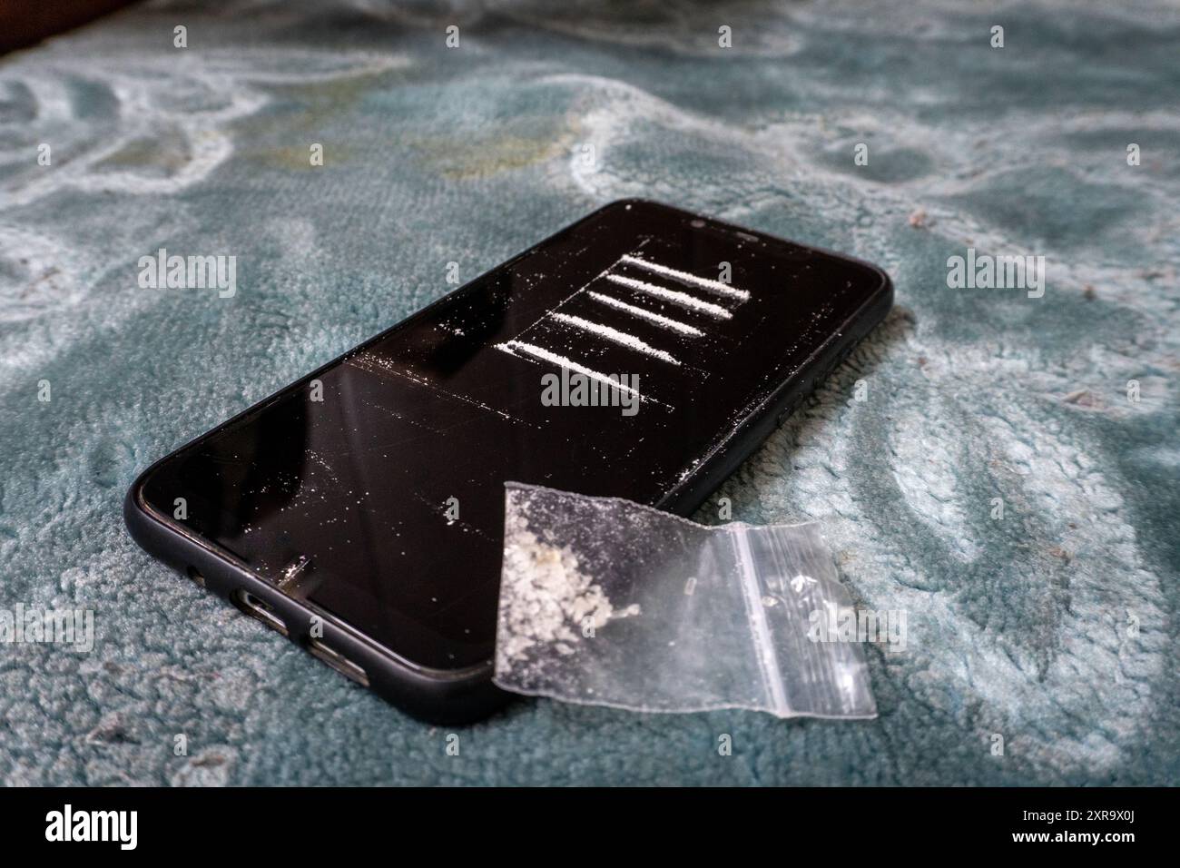 Un primo piano di righe bianche in polvere sullo schermo di un telefono cellulare, che mette in evidenza la questione dell'abuso di sostanze vietate e il suo impatto. Foto Stock