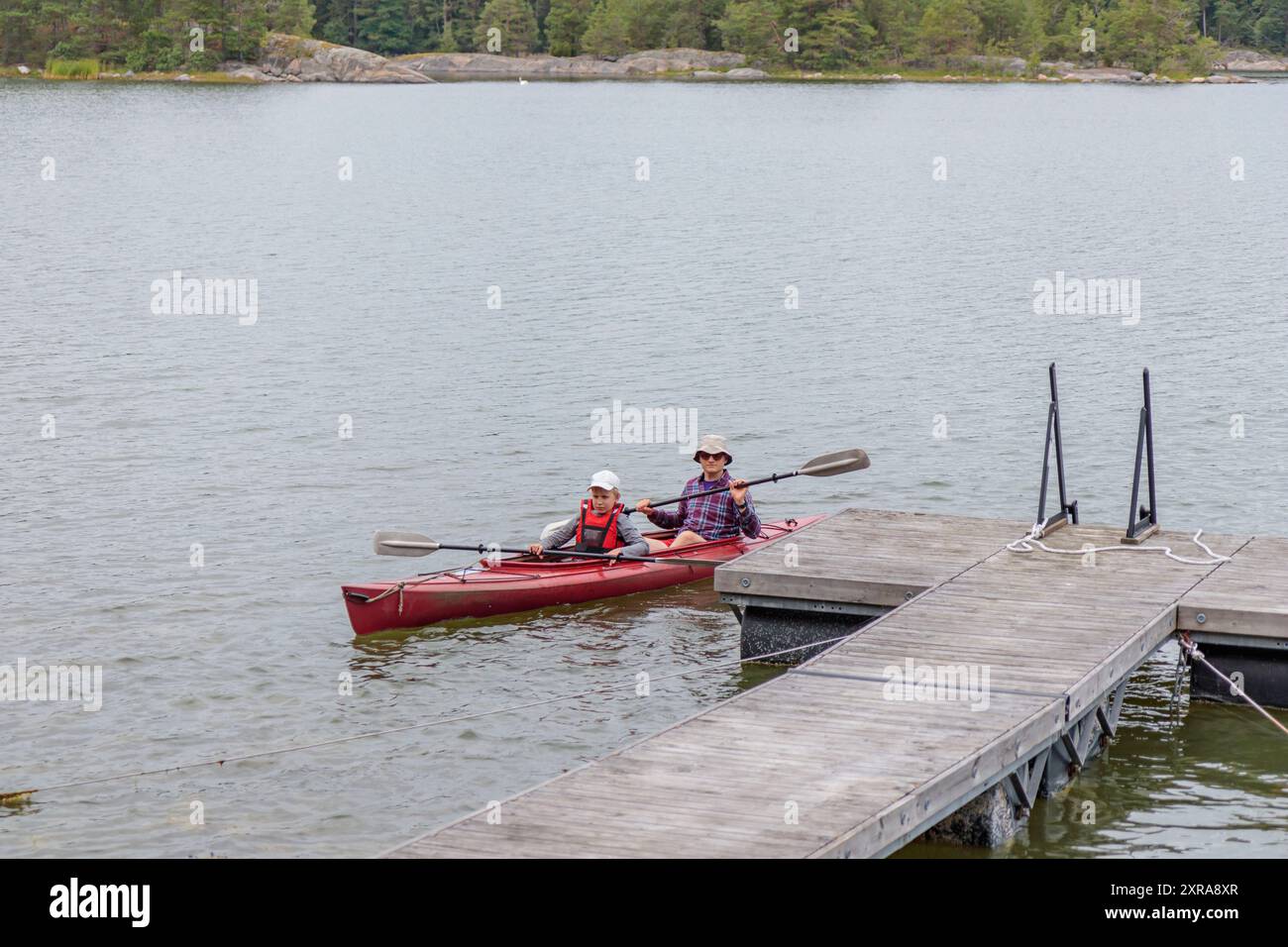 Padre e figlio iniziano a fare kayak con pagaie, kayak, canoa, gite in barca nel Mar Baltico durante le vacanze estive in famiglia in Finlandia, hori Foto Stock