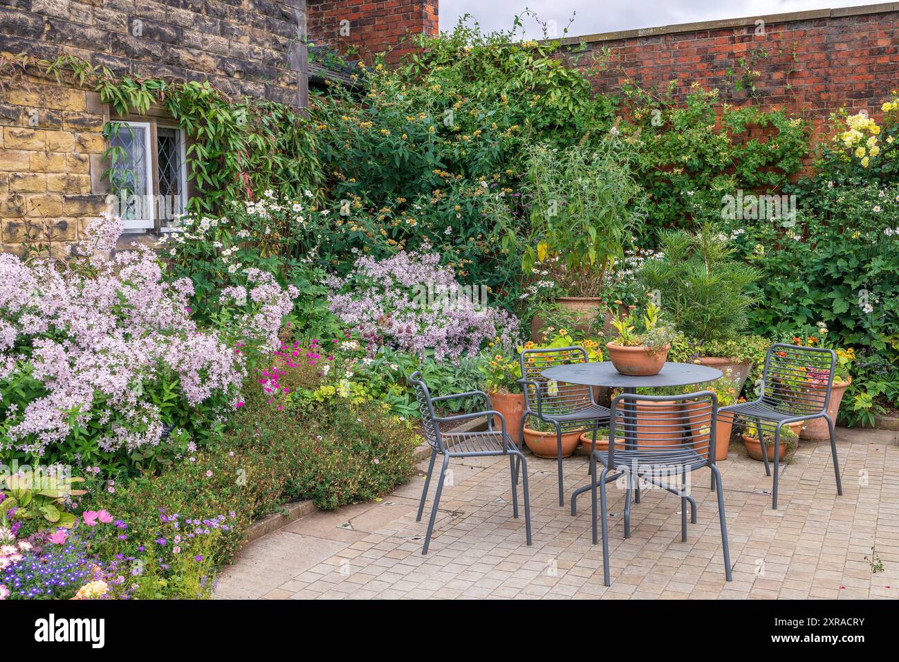 Cottage giardino coperto con tavolo e sedie in metallo. Foto Stock