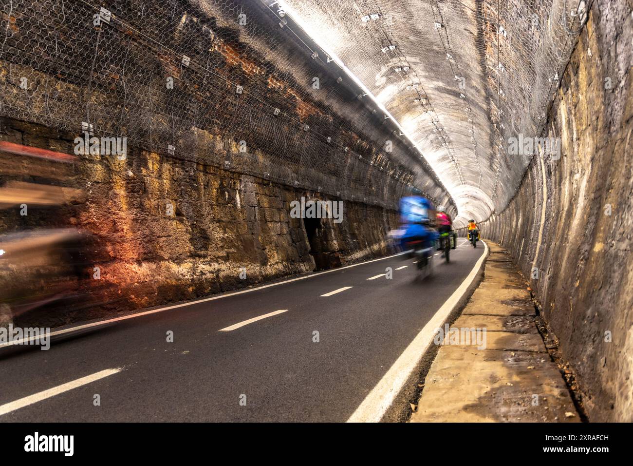 Pedalando attraverso il tunnel della ciclabile dell'alpe adria ( Pontebanna ) attraverso la Val Canale in Italia Foto Stock