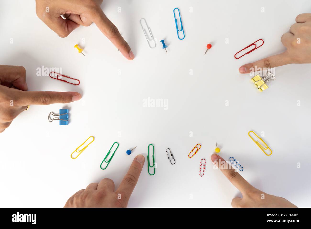 Diverse mani hanno puntato le dita verso il centro. Centrare il cerchio del dito con la graffetta per ufficio. Foto Stock