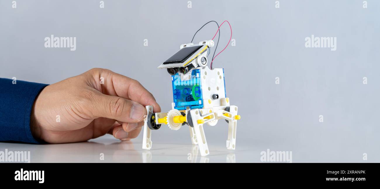 Uomo che inventa la costruzione di robot che imparano le auto insieme nella classe STEM. Studenti felici, bambini che imparano insieme a costruire robot in classe alla scienza Foto Stock