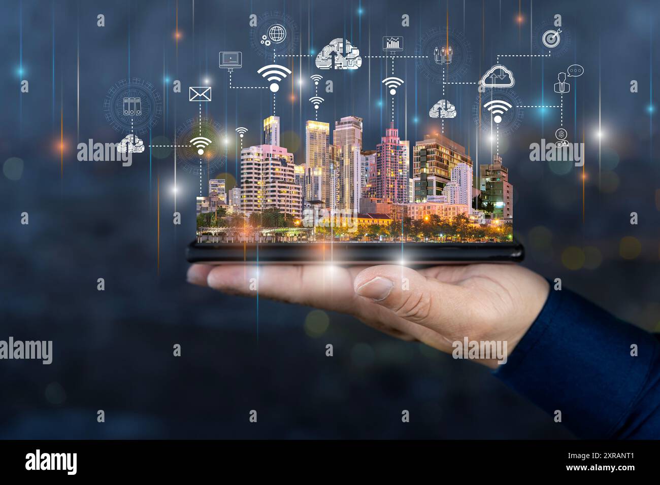 Concetto di tecnologie per le città intelligenti con tablet digitale e grattacieli notturni di megapolis con icone di cloud digitali a mano umana sullo skyline sfocato sul retro Foto Stock