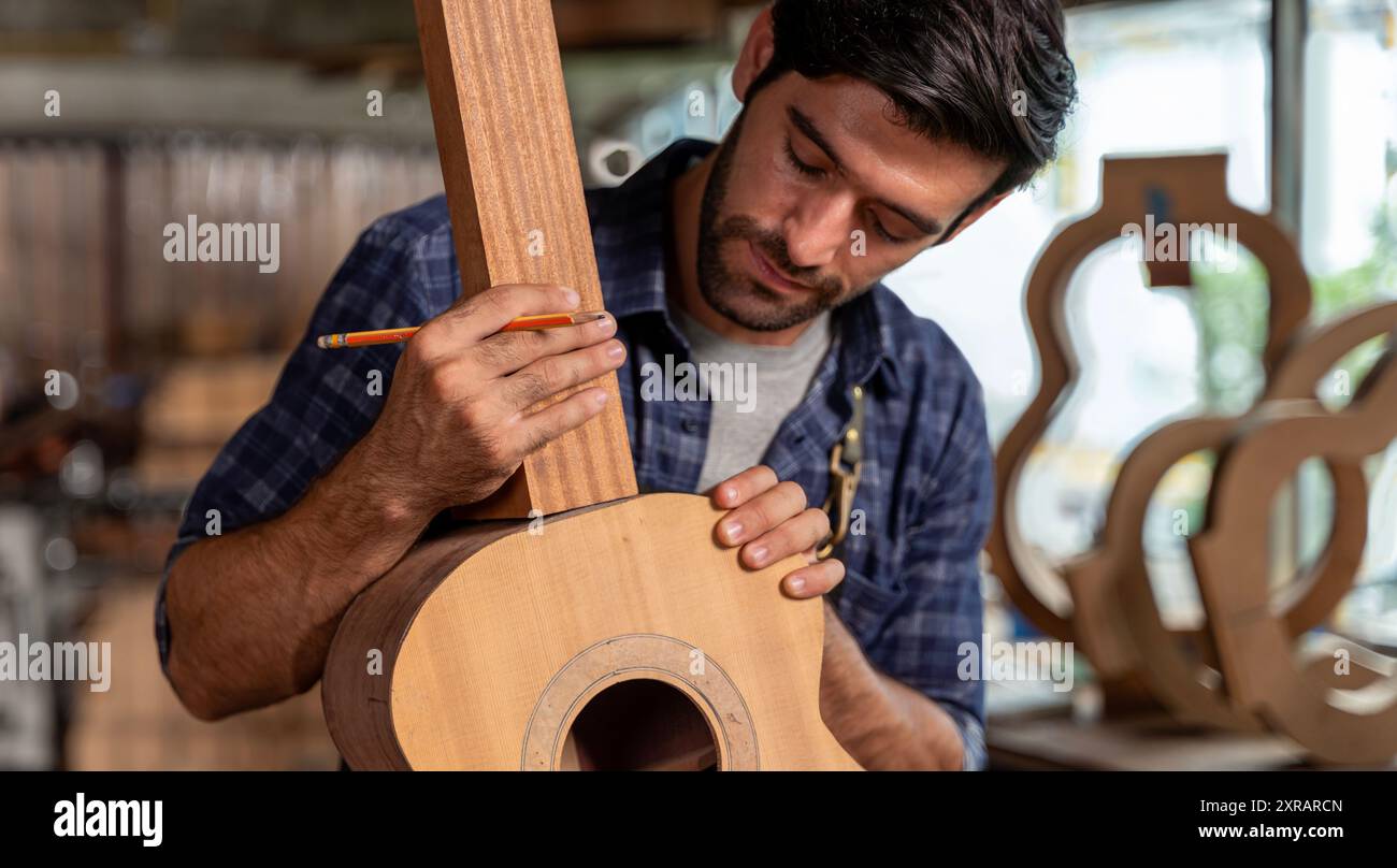 Uomo che produce chitarre acustiche in laboratorio. Il produttore di chitarre asiatiche costruisce chitarre di alta qualità per i musicisti che fanno il negozio di chitarre fatte a mano. fi funzionante Foto Stock