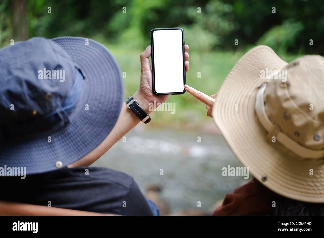 Uomo e donna con le mani che tengono il telefono sullo sfondo del fiume, uomo e donna con uno smartphone mobile vuoto, vista posteriore sulla verde foresta pluviale tropicale landsca Foto Stock