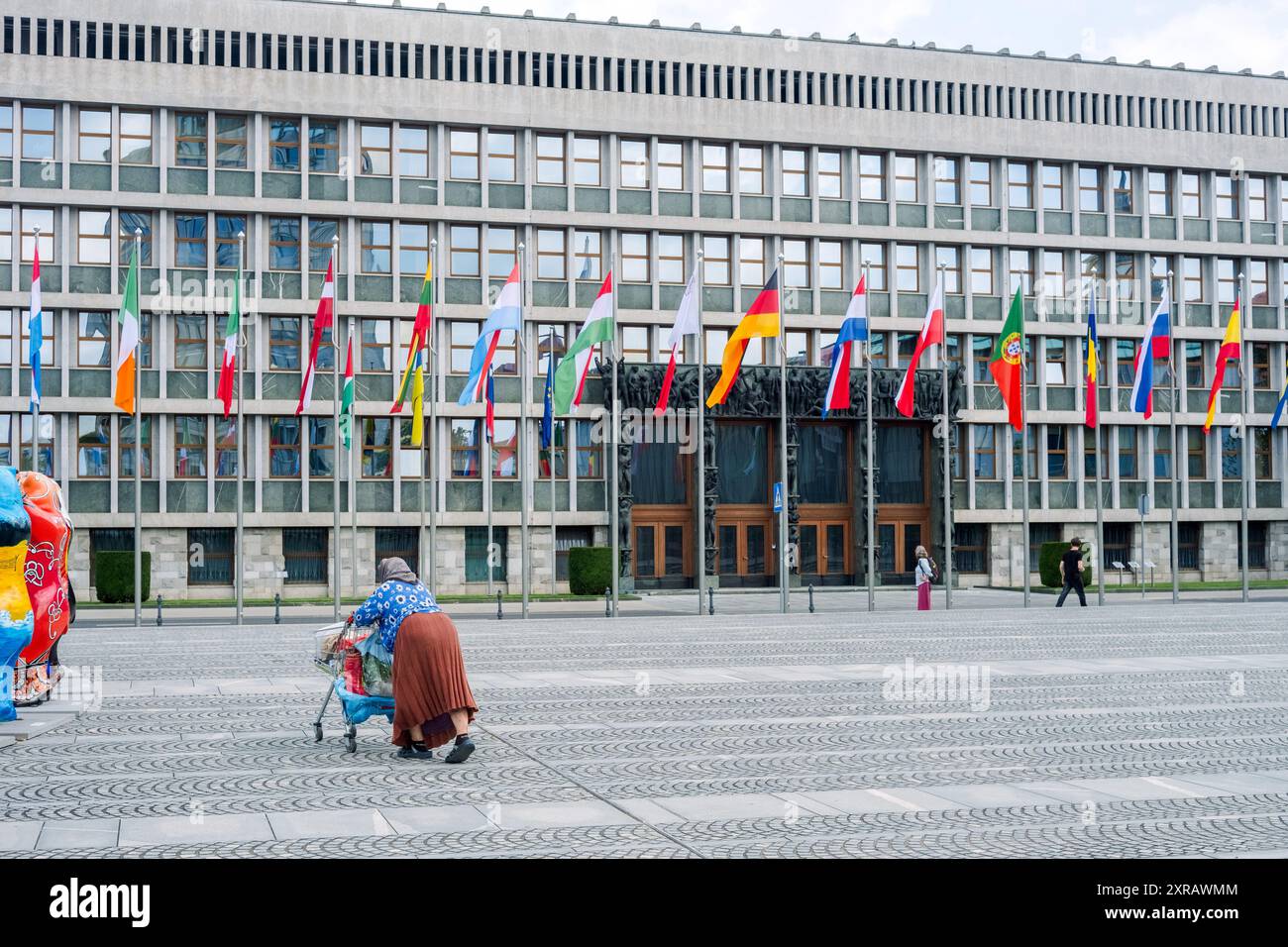 Una senzatetto spinge un carro al Palazzo dell'Assemblea Nazionale della Slovenia Foto Stock