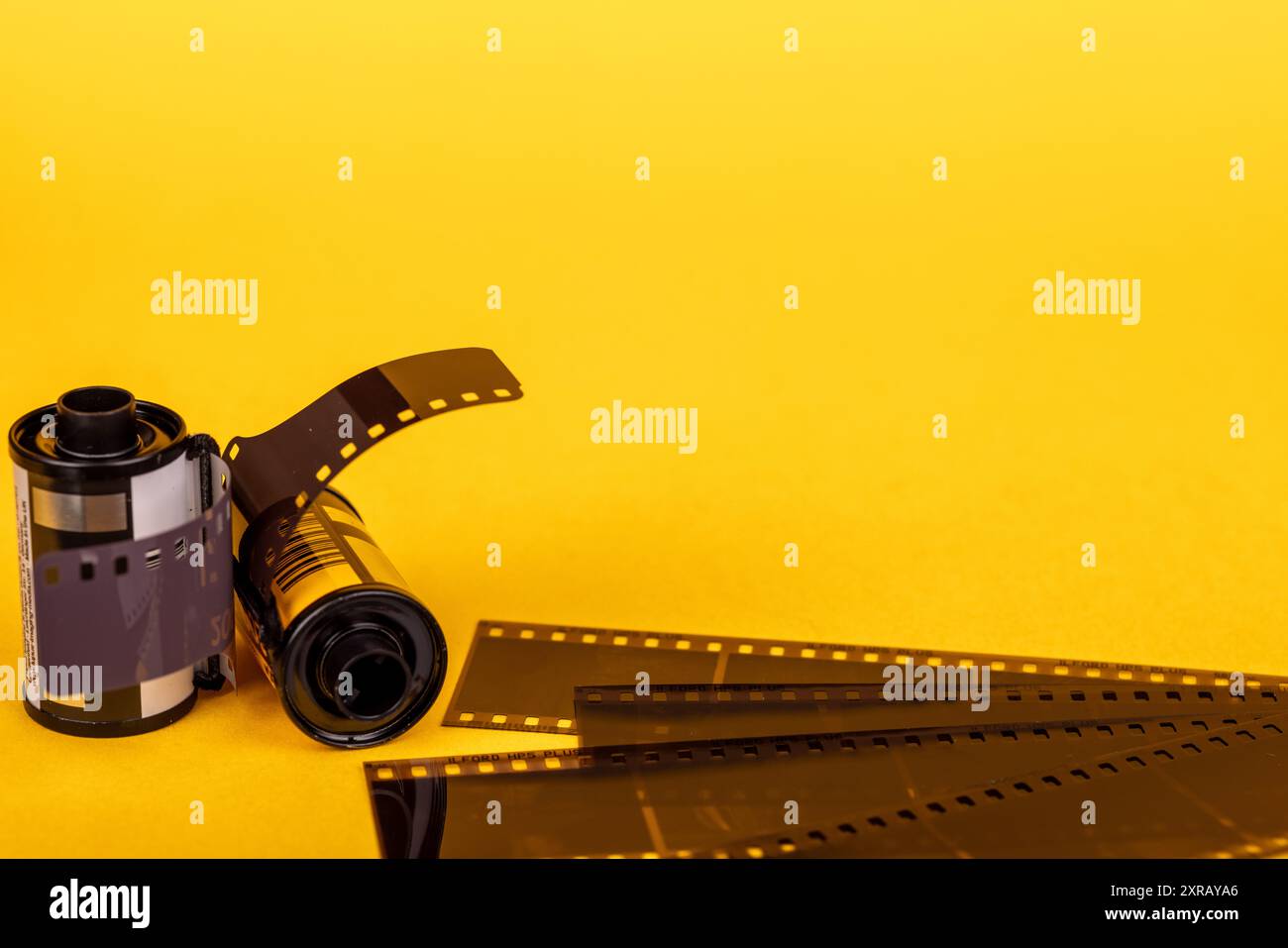 Primo piano di rotoli di pellicole analogiche con stampe sviluppate disposte su una superficie gialla. Una rappresentazione visiva dello sviluppo fotografico classico. Foto Stock
