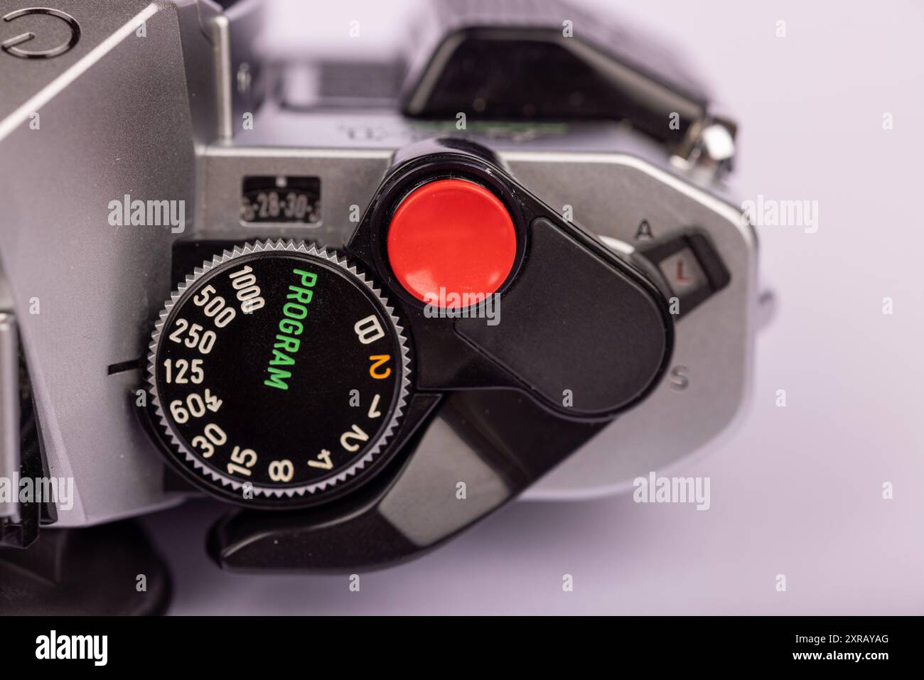 Primo piano di una vecchia fotocamera distesa in piano con un pulsante rosso prominente dell'otturatore. I dettagli vengono acquisiti su uno sfondo bianco pulito. Foto Stock