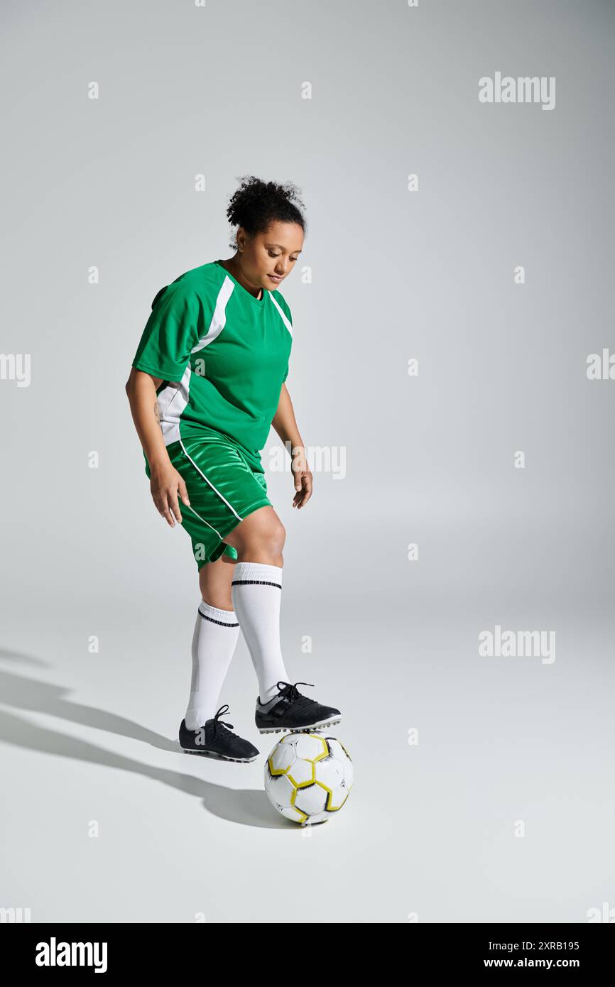 Atleta femminile in maglia verde, bilancia sapientemente la palla a piedi. Foto Stock