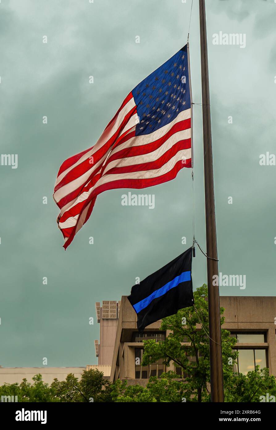 Bandiera degli Stati Uniti e simbolo della polizia "sottile linea blu" sotto un cielo scuro e coperto Foto Stock