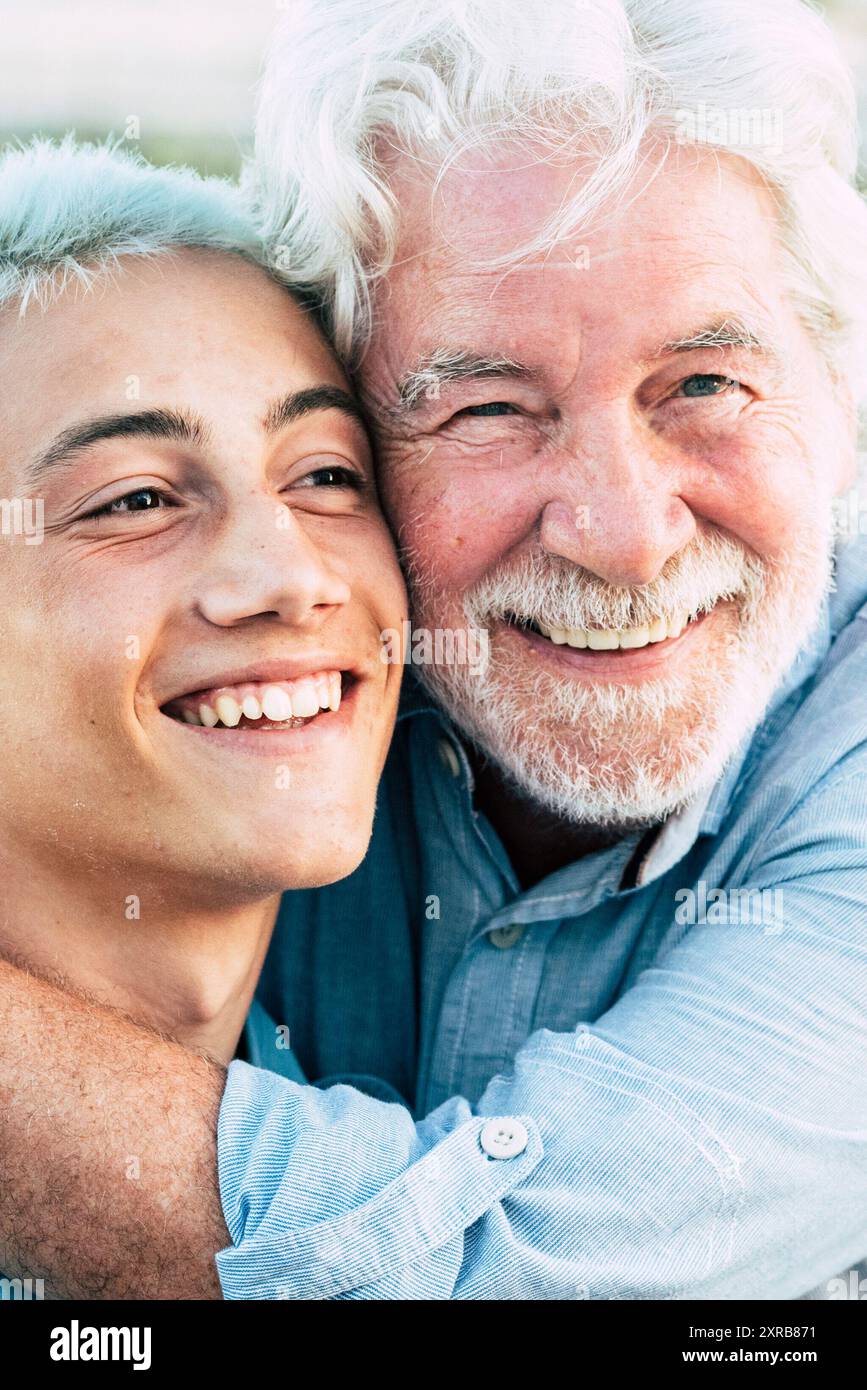 Padre e figlio o nonno e nipote insieme abbracciano e godono con sorriso - allegro caucasico età diversa persone all'aperto - concetto di età e uomini di generazioni miste Foto Stock
