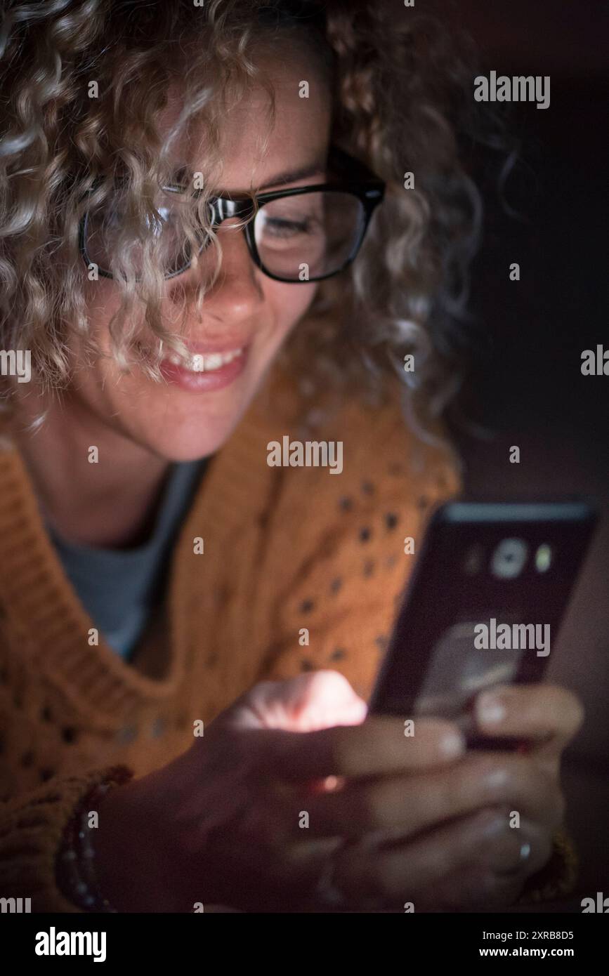 Donna adulta utilizzare il telefono cellulare Internet di notte da solo a. casa - persone e dipendenza dalla tecnologia - connessione e. concetto di conferenza telefonica - consente di cercare il web femminile con occhiali Foto Stock