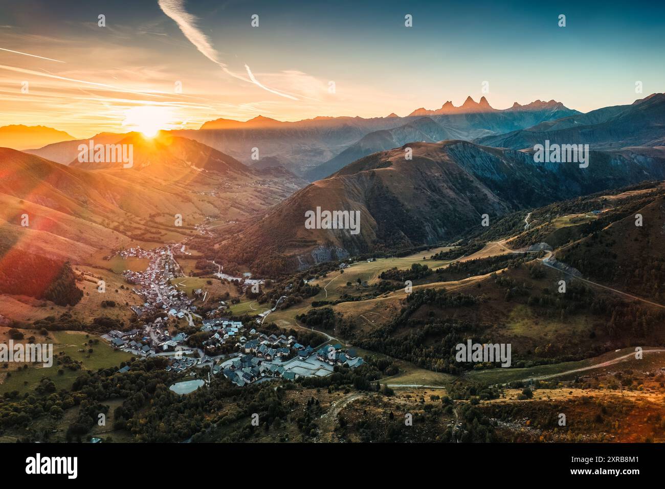 Vista aerea dell'alba sul massiccio dell'Arves tra le Alpi francesi con la città sciistica nella valle in autunno a Lac Guichard, Francia Foto Stock