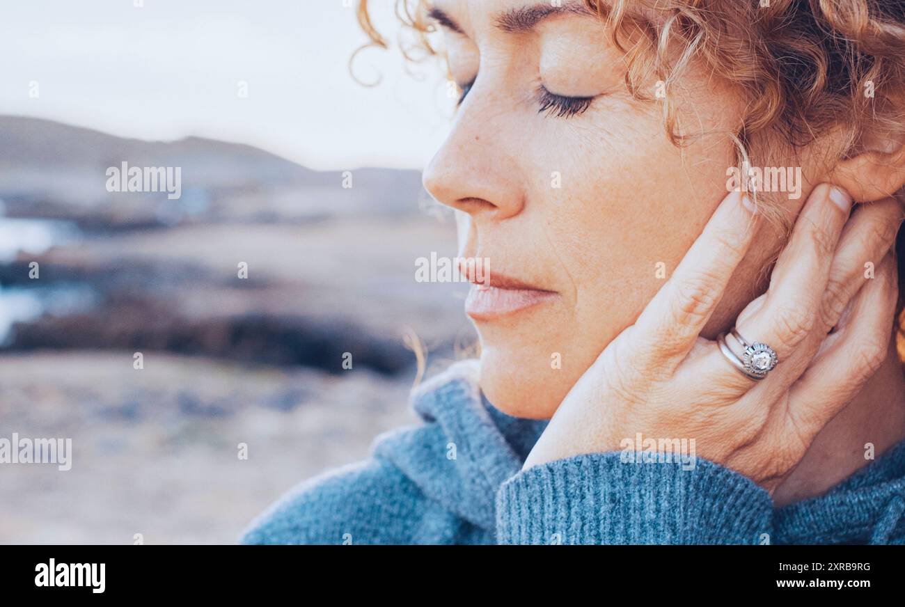 Ritratto di una giovane donna, bionda con capelli ricci, con gli occhi chiusi, triste e malinconica. Concetto di inverno, tristezza, malinconia. Foto Stock