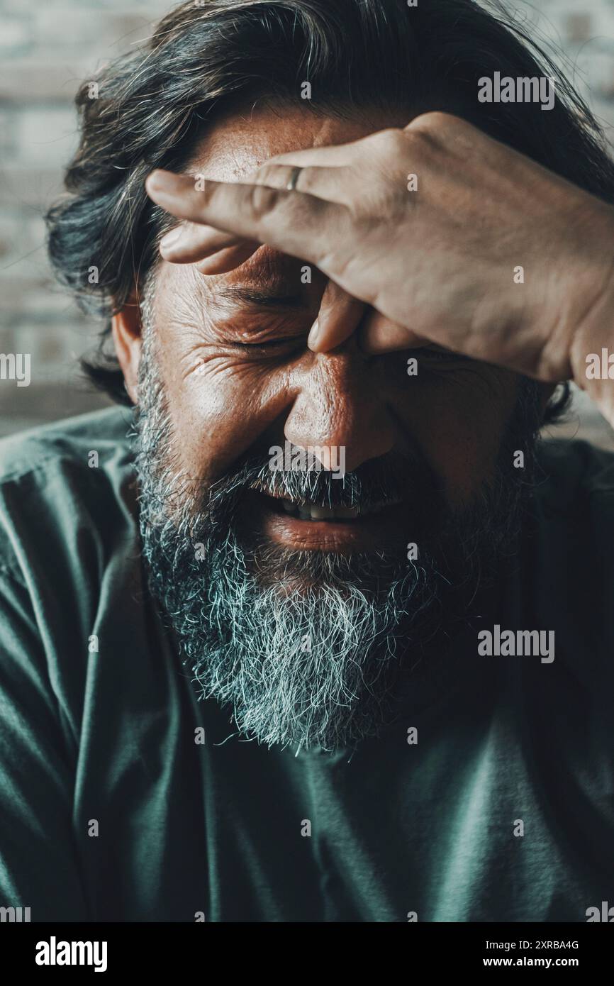 Mal di testa e emicrania concetto malsano. Uomo che tocca la sua parte anteriore e fa un'espressione dolorosa per problemi e dolori. Persone stressate e preoccupate a casa al chiuso. Ritratto di uomo con sintomi influenzali influenza influenza Foto Stock
