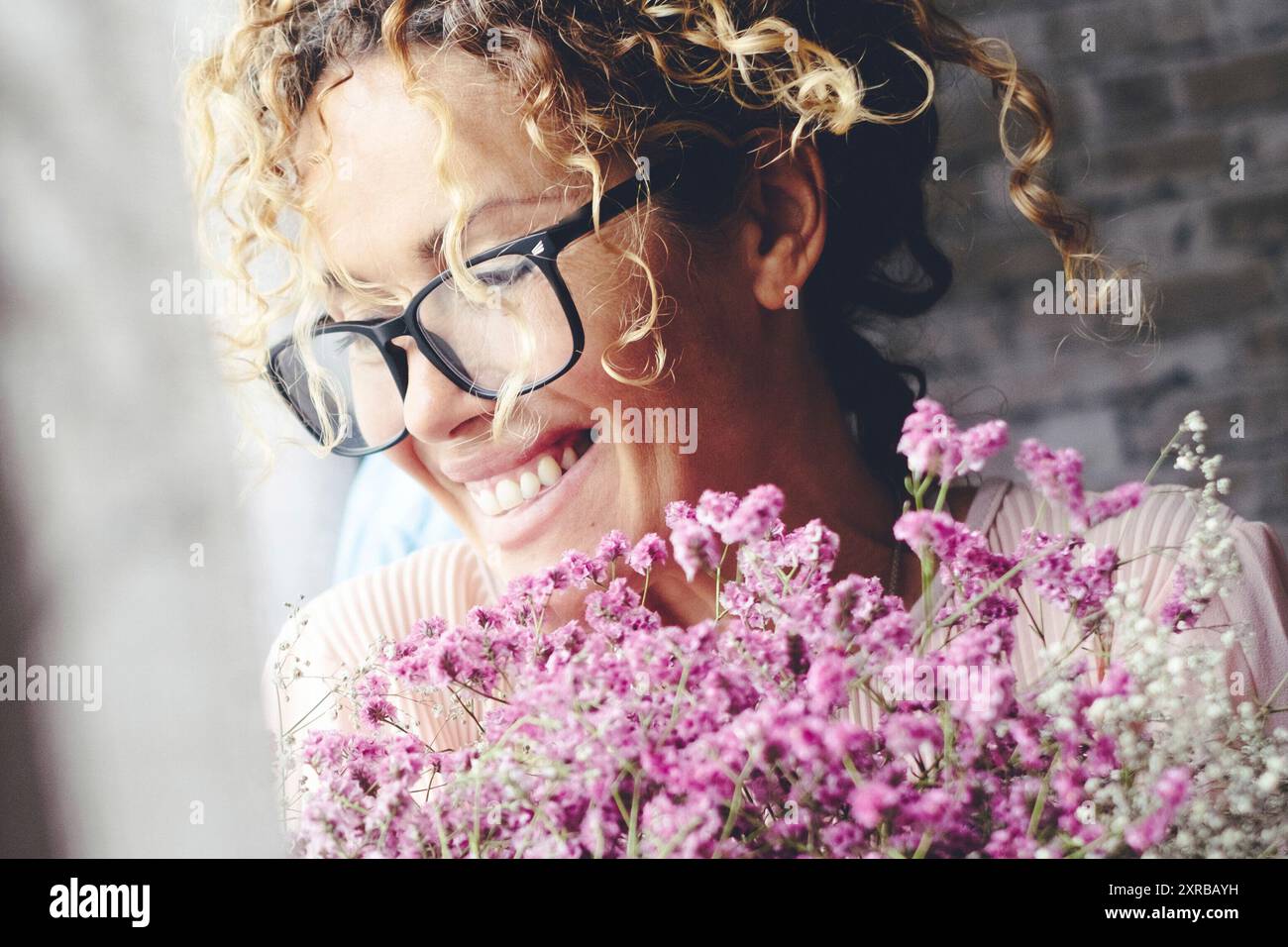 Una giovane donna entusiasta e felice a casa con un grande bouquet di fiori. Celebrazione dell'anniversario e del compleanno della felicità persone femminili. Amore e relazione. Nuovo fidanzato che riceve un regalo a casa Foto Stock
