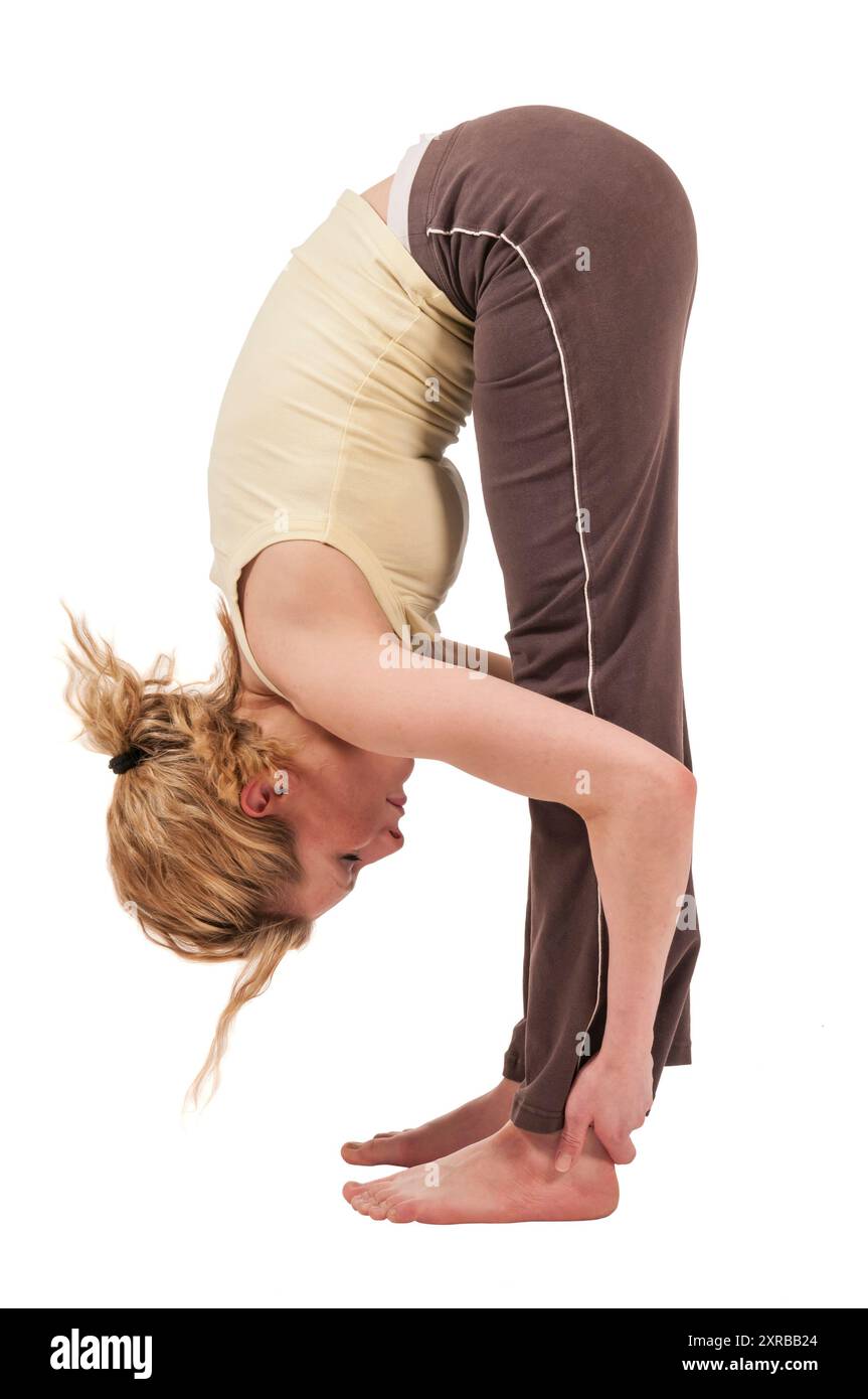 Profilo Vista completa del corpo di una giovane donna in abito sportivo che fa esercizio di yoga in piedi in avanti piega Pada Hastasana con le braccia tese alle caviglie. Foto Stock