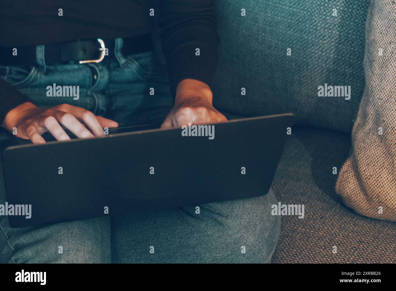 Una giovane donna che utilizza il laptop di notte a casa, seduta sul divano, cerca sul Web e lavora fino a tardi. Le donne utilizzano la tecnologia del computer con connessione wireless per il lavoro o il tempo libero per le attività al chiuso Foto Stock