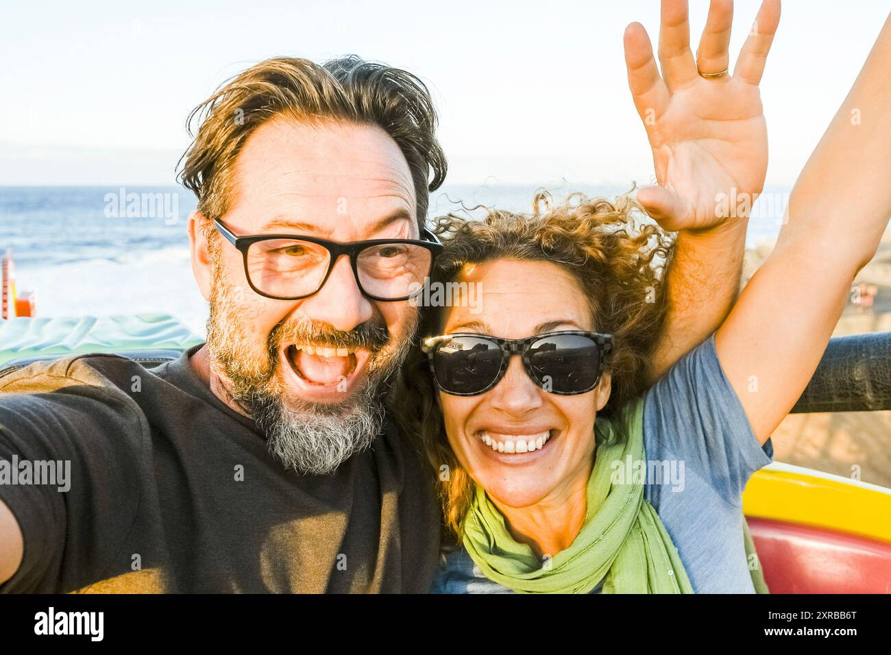 Coppia sulle montagne russe divertirsi con le braccia in aria divertendosi ed emozionandosi per divertirsi insieme. Soleggiata vacanza pomeridiana. Concetto di tempo libero e allegria persone felici Foto Stock