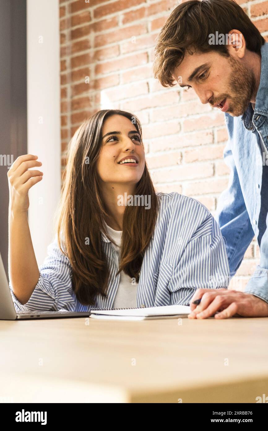 Una giovane coppia millennial che lavora insieme al desktop con un notebook e un'azienda online. Uomo e donna adulti che usano il computer sul tavolo a casa, in ufficio, sul posto di lavoro di piccole imprese. Stile di vita Foto Stock