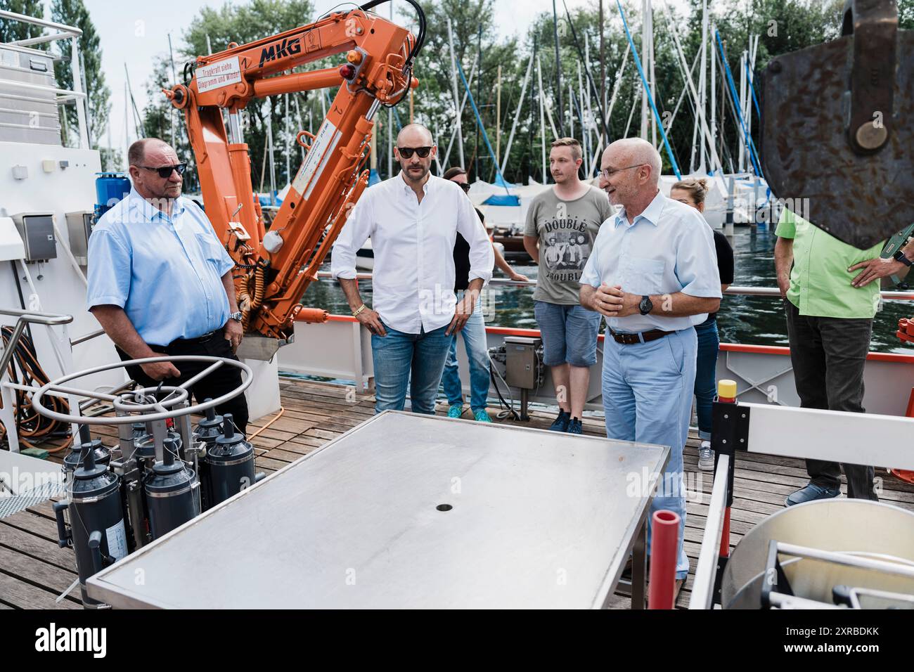 Danyal Bayaz, ministro delle Finanze del Baden-Wuerttemberg, ha condotto una serie di visite l'8 agosto 2024, come parte del suo tour estivo in tutto lo stato. Si è concentrato sulla ricerca ambientale e su iniziative sportive inclusive. Durante il suo tour, Bayaz ha visitato l'Institute for Lake Research (ISF) dell'Istituto statale per l'ambiente Baden-Wuerttemberg (LUBW) a Langenargen. Fu accompagnato da Klaus Hoher, un membro del parlamento di stato (MDL), e accolto dal dottor Ulrich Maurer, presidente della LUBW, e dal dottor Harald Hetzenauer, capo della ISF. Le discussioni durante questa visita evidenziano Foto Stock