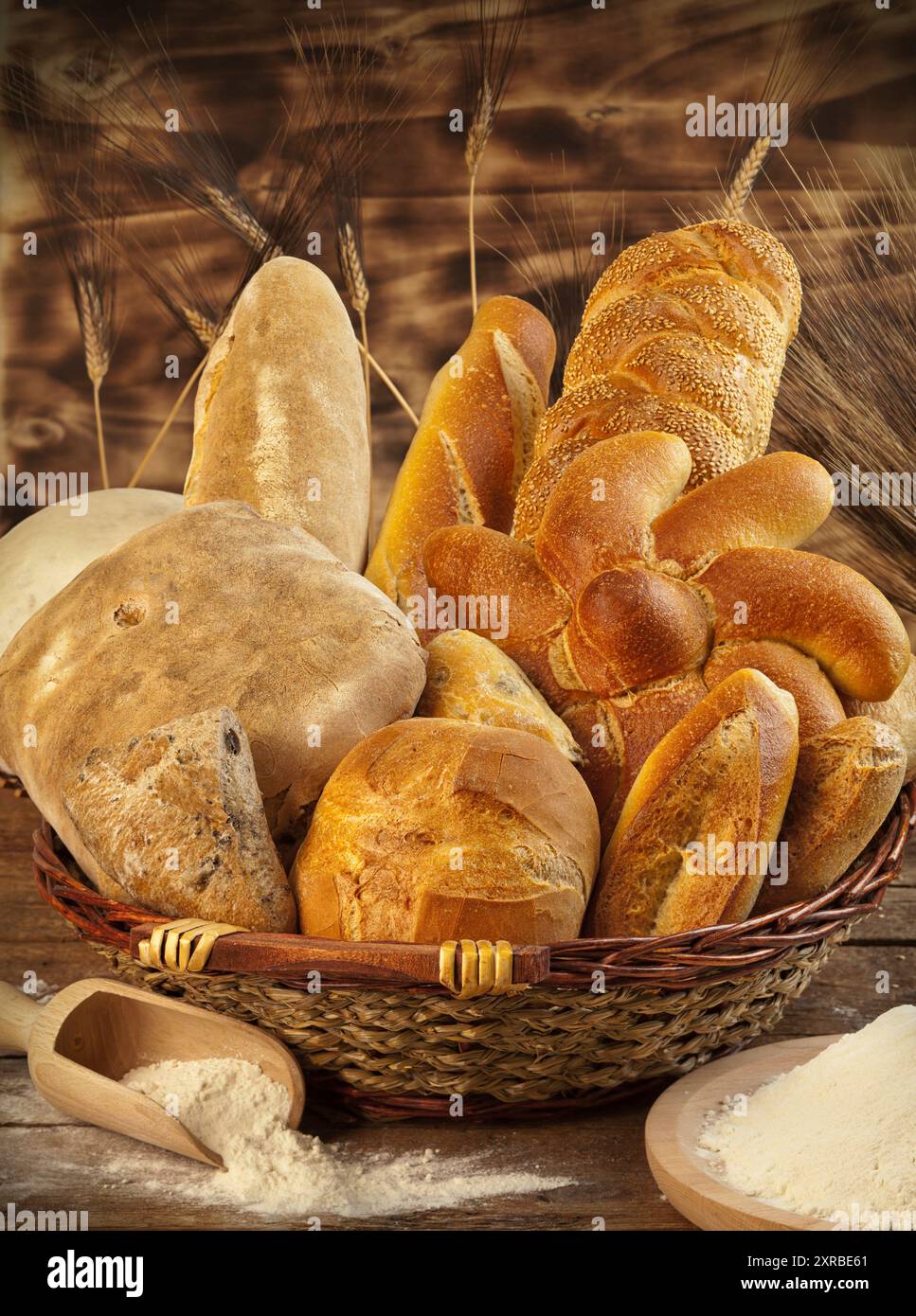 Cesto in Vimini con diversi tipi di pane su un tavolo di legno. Foto Stock