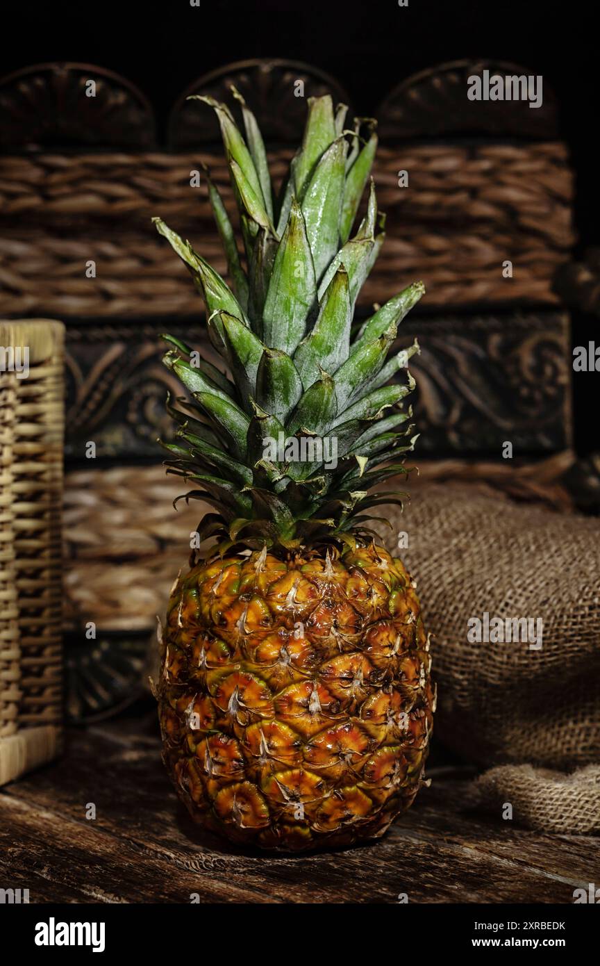 Natura morta con ananas su legno tavolo rustico con sacco di iuta sullo sfondo. Foto Stock