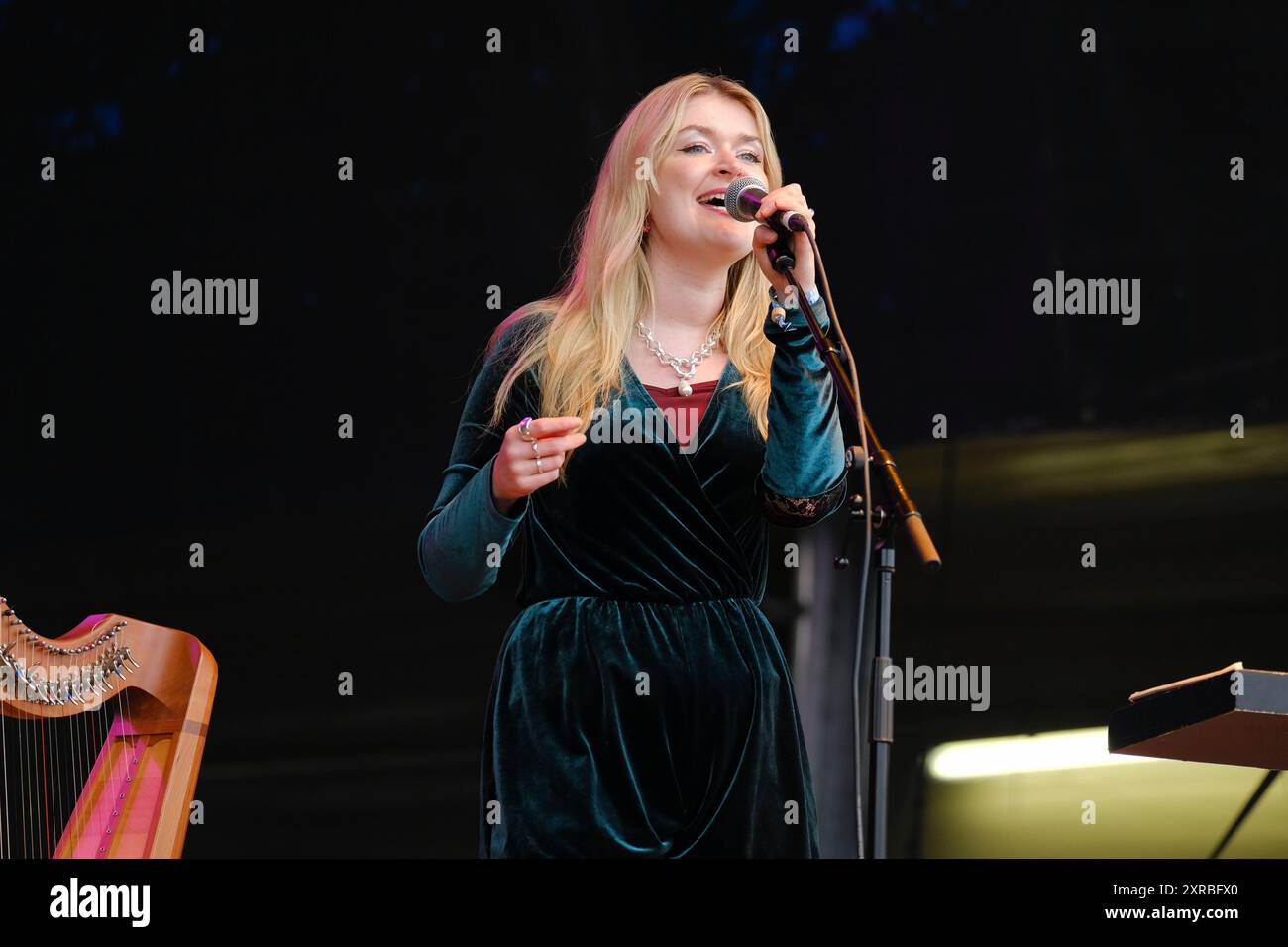 Williamscot, Regno Unito. 8 agosto 2024. Josie Duncan arpa e voce che si esibiscono dal vivo sul palco con Kathryn Tickell e The Darkening alla Cropredy Convention. Kathryn Tickell è una compositrice, interprete ed educatrice. Il Darkening, che prende il nome dalla vecchia parola northumbriana per il crepuscolo, comprende quattro membri con sede nel nord-est dell'Inghilterra Amy Thatcher, Joe Truswell alla batteria, Kathryn Tickell alla voce e alle pipe settentrionali, Kieran Szifris alla chitarra e al mandolino, Josie Duncan arpa e voce. Credito: SOPA Images Limited/Alamy Live News Foto Stock