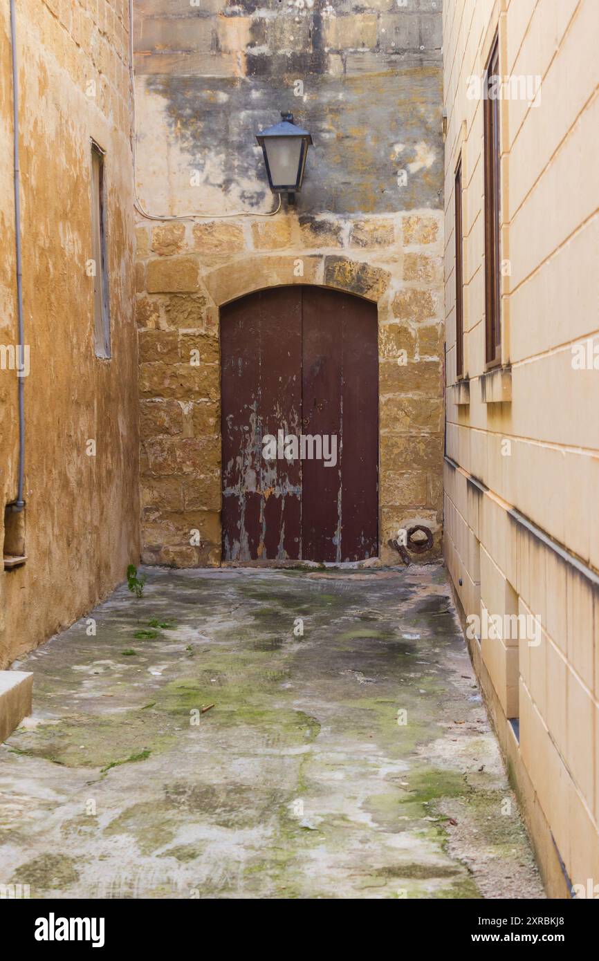 Vecchio edificio con porte chiuse in legno e mura storiche in un vicolo all'aperto Foto Stock
