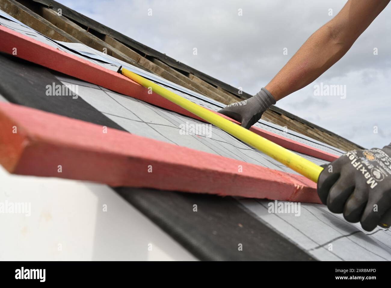 Lavori di costruzione di tetti, costruttore che utilizza un metro a nastro per misurare la distanza tra due listelli di legno, Regno Unito Foto Stock