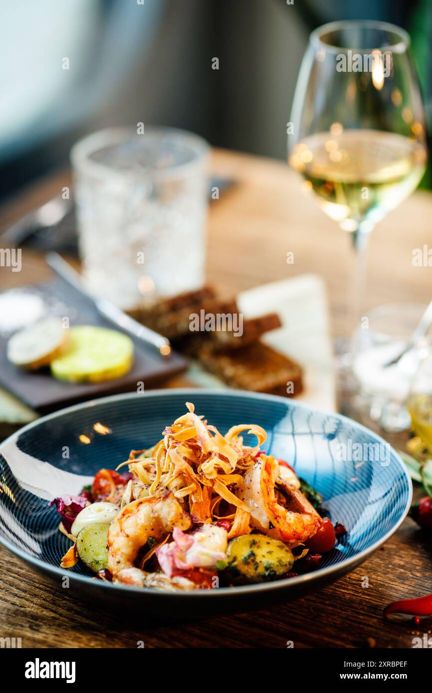 Insalata calda con gamberi argentini. Patate alle mandorle, lattuga romana mini, carota, pomodoro ciliegia, pesto, radici nere, noce caramellata, barbabietola Foto Stock