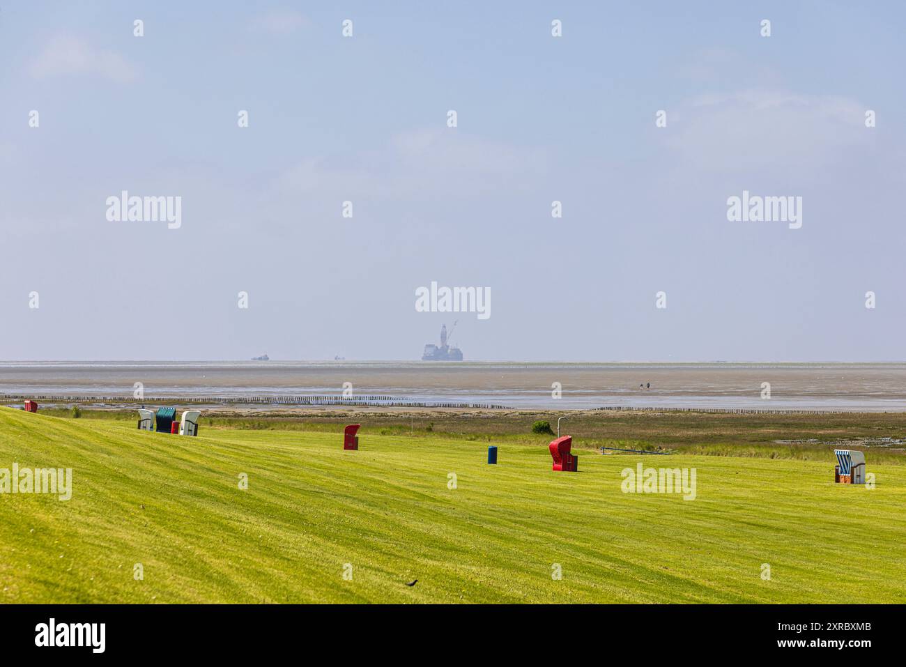 Spiaggia balneare sul Mare del Nord al largo di Friedrichskoog Point a Dithmarschen, con l'impianto di produzione di olio Mittelplate all'orizzonte a destra, Schleswig-Holstein, Germania Foto Stock