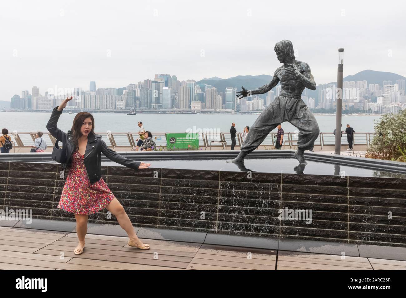 Cina, Hong Kong, Kowloon, Tsim Sha Tsui, Chinese Tourist in posa davanti alla statua di Bruce Lee Foto Stock