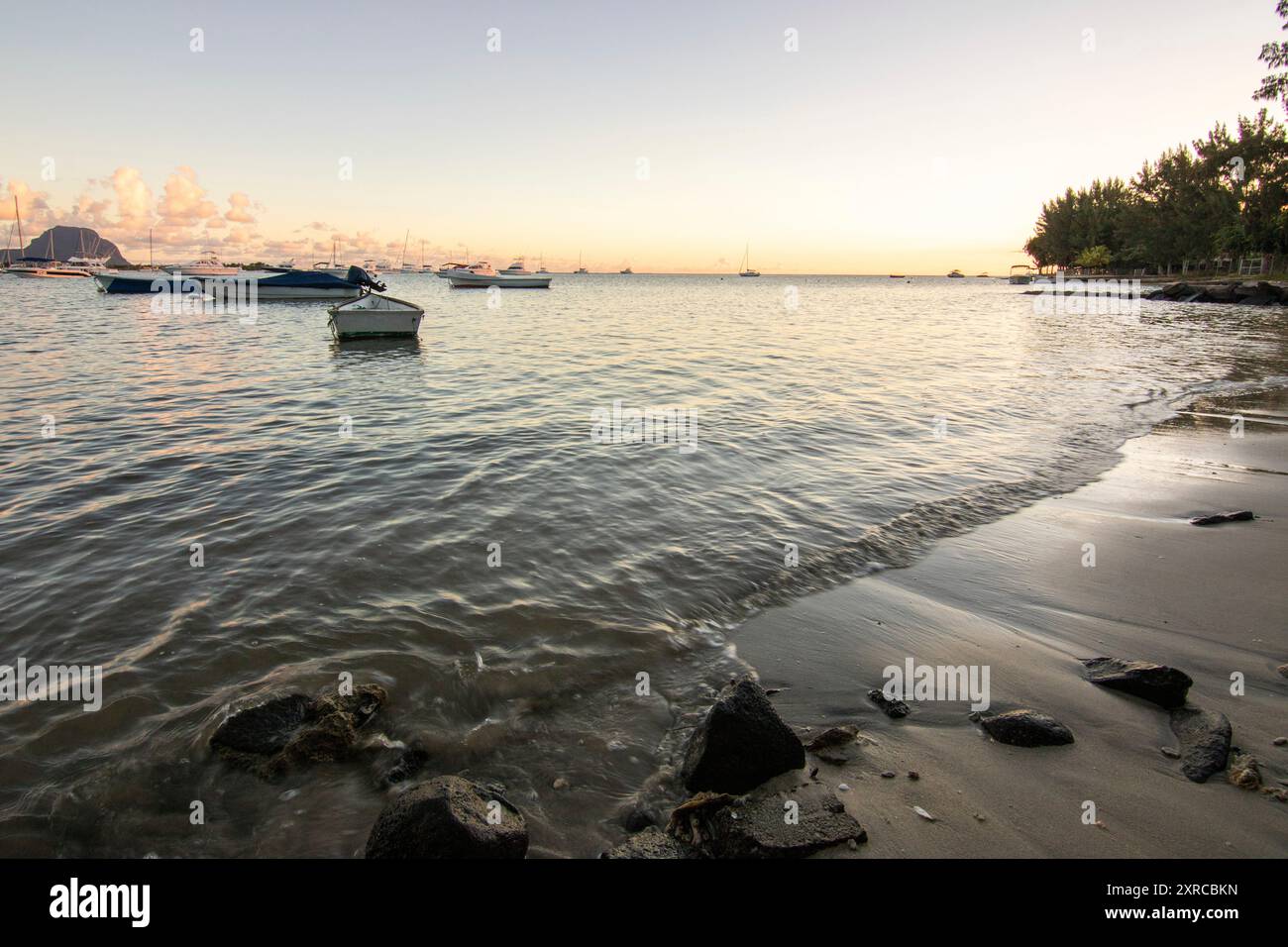 Tramonto su una splendida spiaggia di sabbia con vista dell'Oceano Indiano, del mare e del paesaggio tropicale, vacanza sulla spiaggia di Flic en Flac, Mauritius, Africa Foto Stock