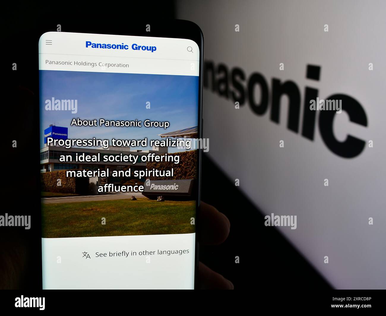 Persona che tiene un cellulare con la pagina web della società giapponese Panasonic Holdings Corporation davanti al logo. Messa a fuoco al centro del display del telefono. Foto Stock