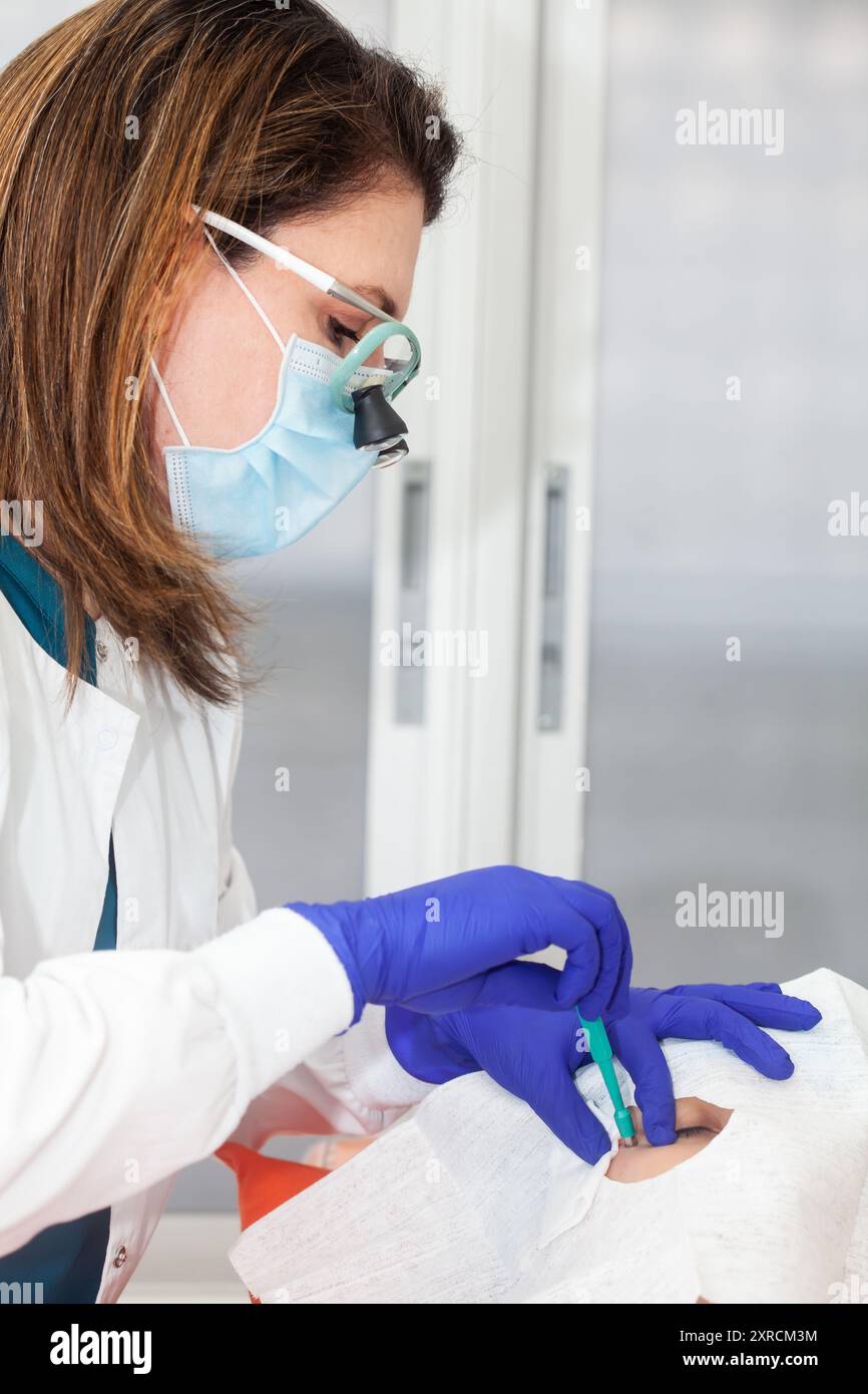 Procedura di rimozione delle lesioni cutanee. Dermatologo che esegue una rimozione di lesione cutanea benigna sul viso di un giovane paziente di sesso maschile. Punch bioptico Foto Stock