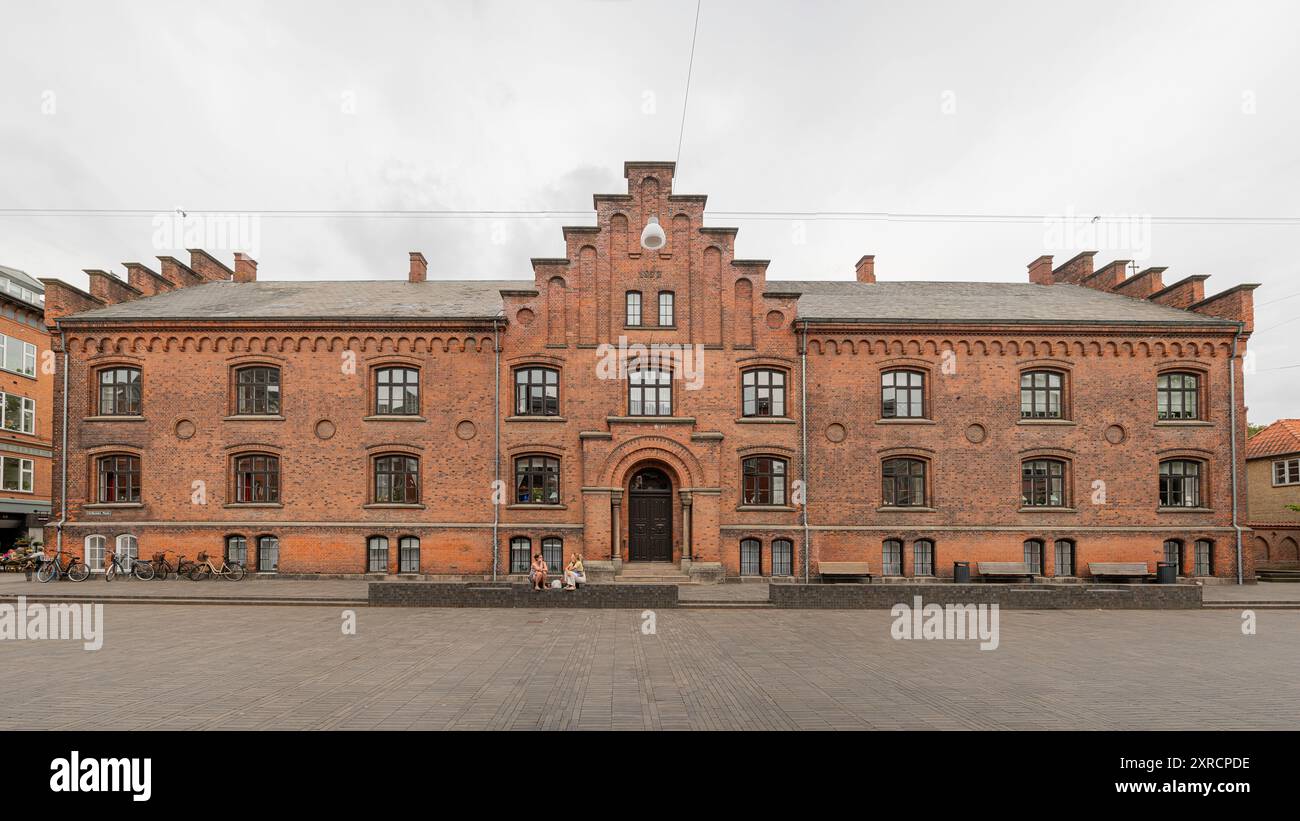 In Piazza del frate Grigio a Odense due ragazze sono sedute di fronte all'edificio del monastero, Danimarca, 3 agosto 2024 Foto Stock