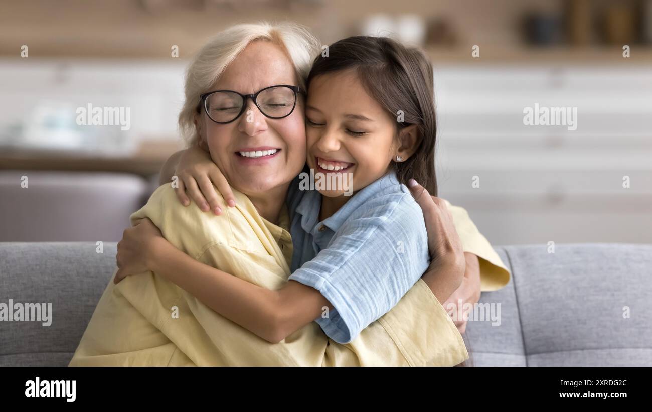 Allegra e carina nipote e felice nonna che abbraccia con amore Foto Stock