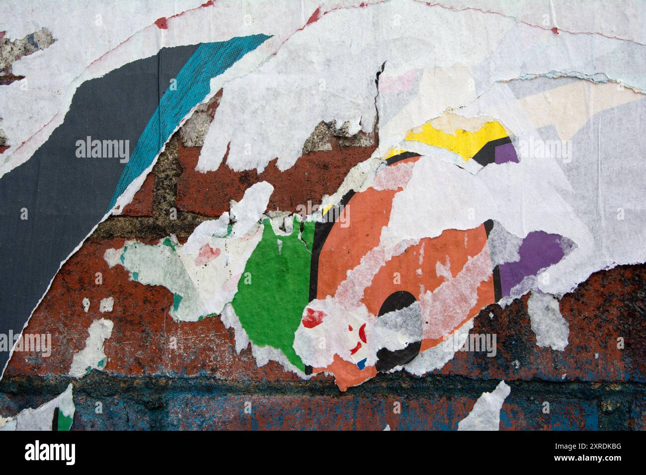 strati di poster staccabili su una parete di mattoni, colore e trama della carta Foto Stock