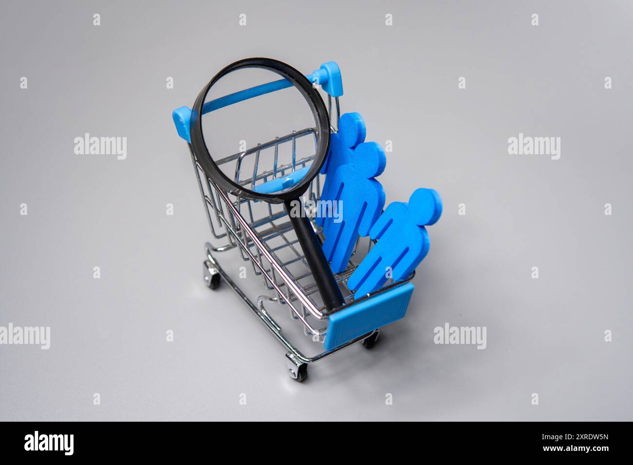 Carrello della spesa in miniatura, statuette e lente di ingrandimento. Segmentazione del mercato e concetto di analisi dei clienti. Foto Stock