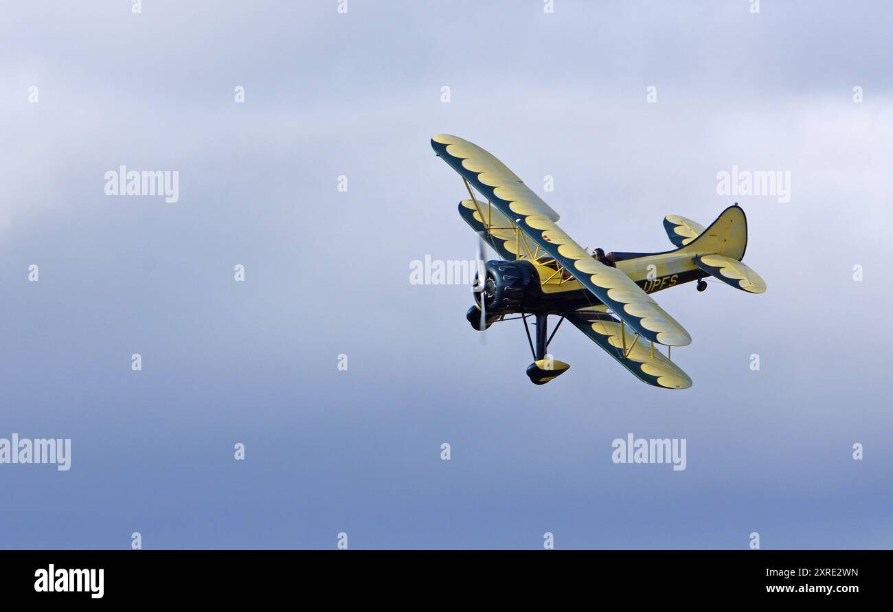 Biplano vintage Waco UPF-7 in volo contro le nuvole. Foto Stock