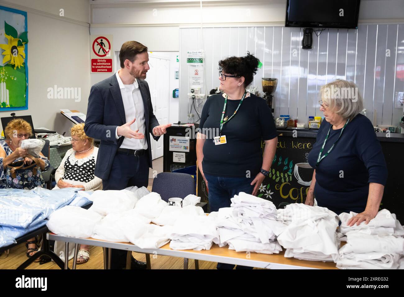 Cradley Heath, West Midlands, Regno Unito. Sabato 10 agosto 2024. Alex Ballinger, deputato laburista per Halesowen nella Black Country, visita un'uniforme scolastica secondaria in un centro comunitario a Cradley Heath, un'area economicamente in difficoltà nella Black Country, West Midlands. Migliaia di uniformi scolastiche locali vengono donate, lavate, avvolte e donate alla popolazione locale per riutilizzarle per aiutare a fronteggiare la crisi del costo della vita. Crediti: Peter Lopeman/Alamy Live News Foto Stock