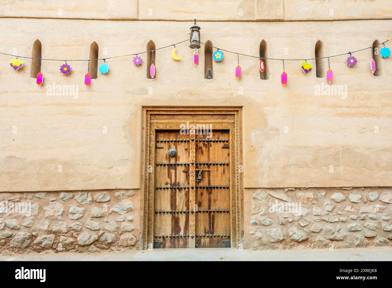 Strada con vecchi edifici in pietra e porte in legno decorate in modo tradizionale, Nizwa, sultanato dell'Oman Foto Stock