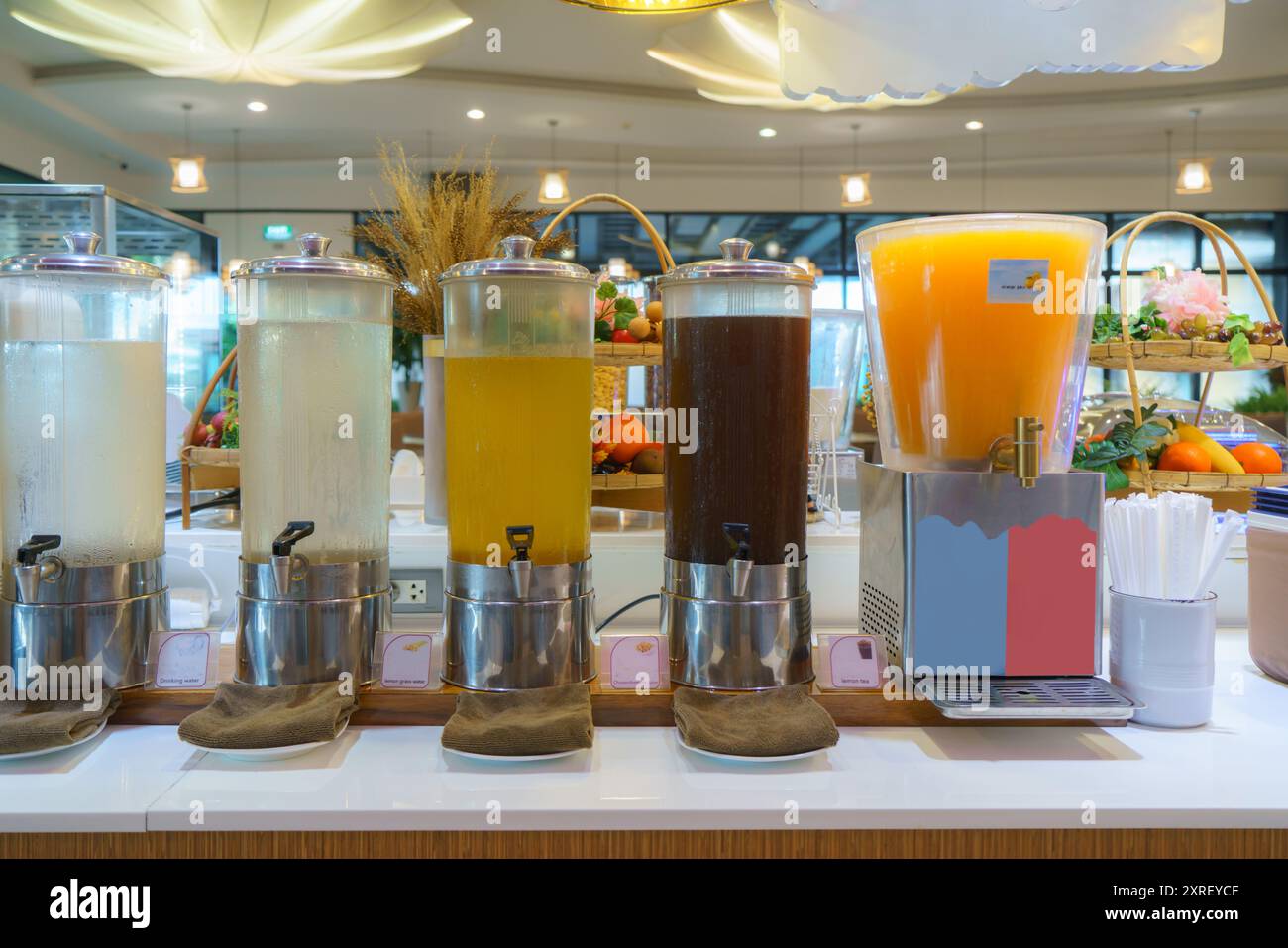 una fila di distributori di bevande a buffet per la colazione. La configurazione include quattro grandi erogatori, ciascuno riempito con un diverso tipo di bevanda Foto Stock