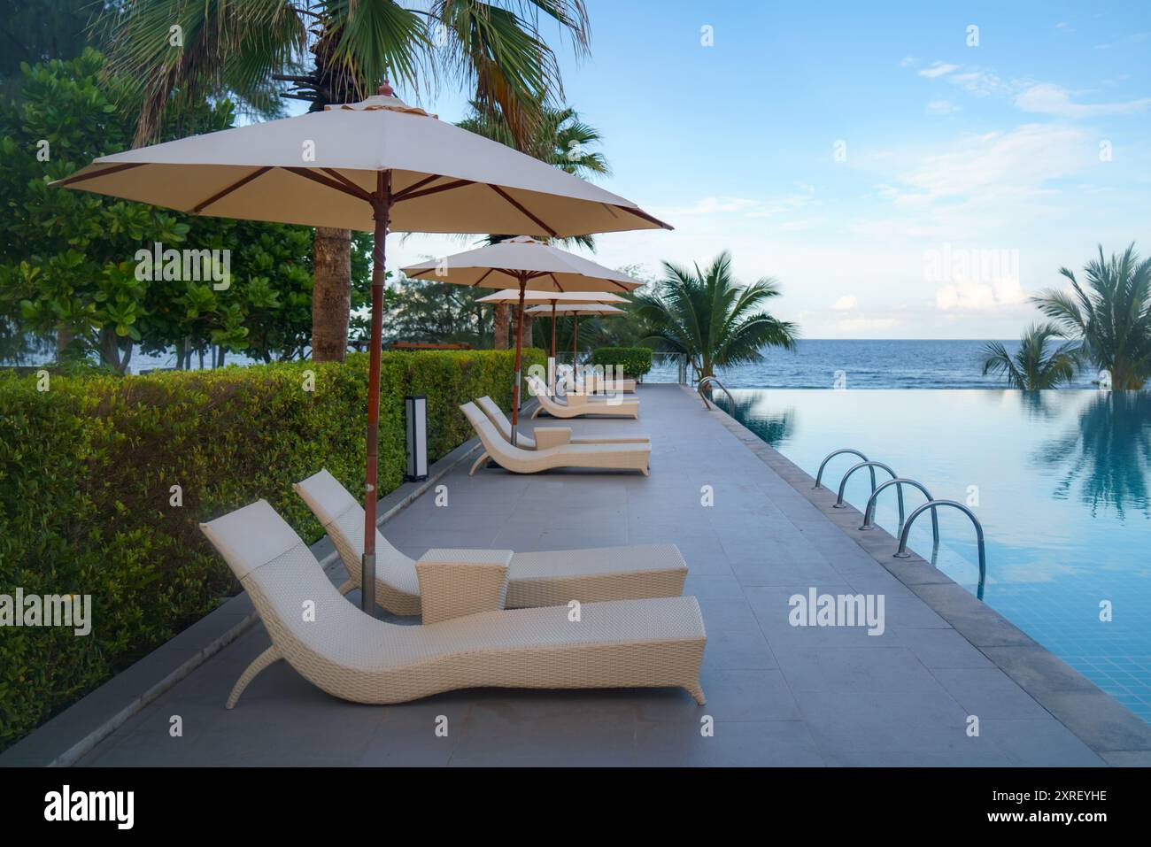 Giardino con sedie a sdraio e area salotto vicino alla piscina Foto Stock