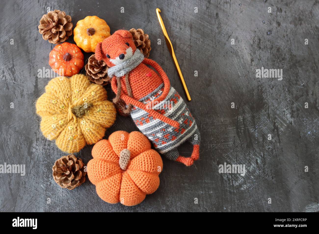 Decorazione di Halloween con zucche, giocattolo Fox all'uncinetto e filato di lana arancione su sfondo grigio con spazio per il testo. Regalo autunnale fatto a mano. Foto Stock