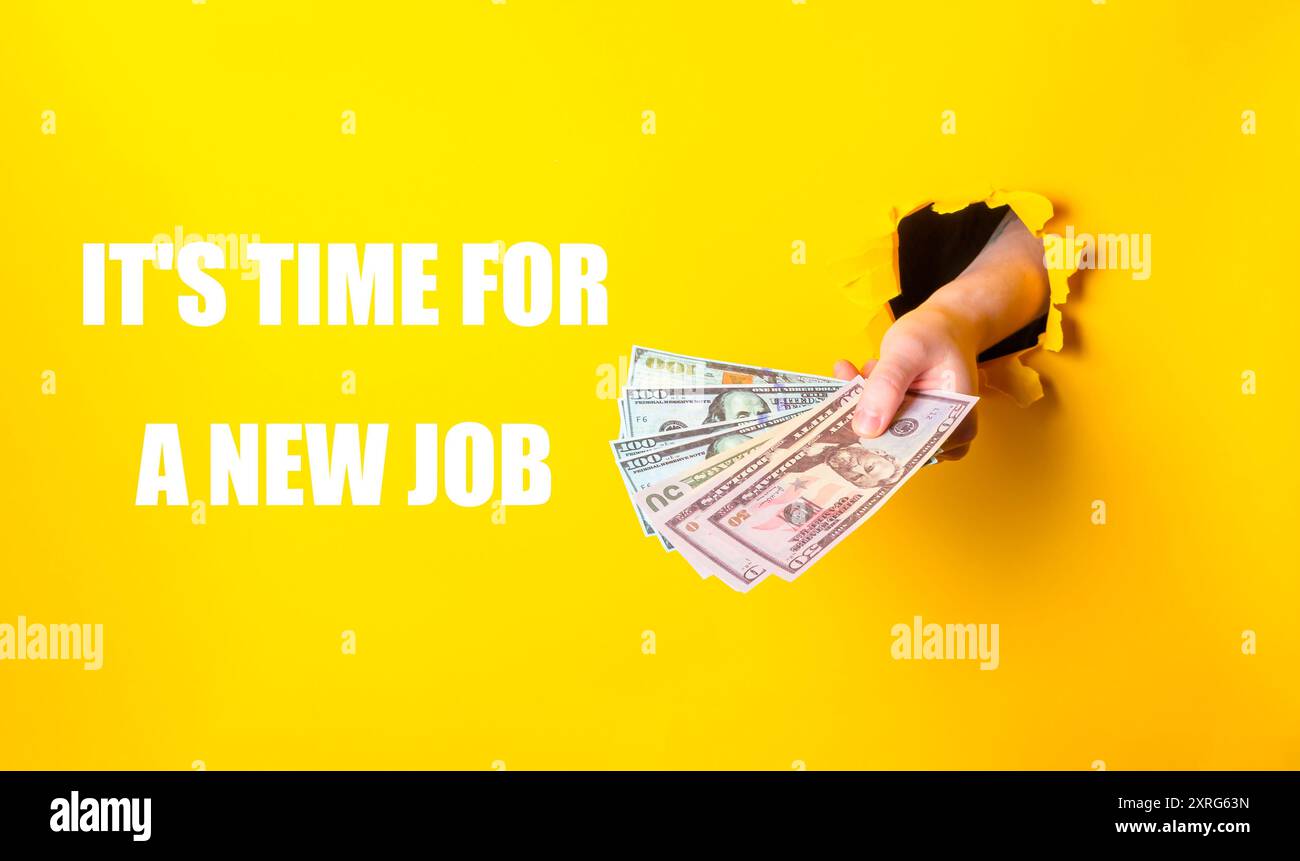 Una mano tiene una pila di soldi, con le parole che è il momento di un nuovo lavoro scritte di seguito, suggerendo la motivazione per il cambiamento di carriera e il miglioramento finanziario Foto Stock