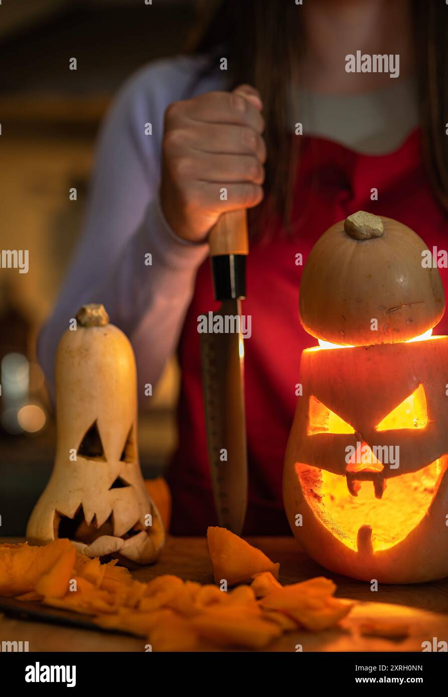 Ragazza che crea una decorazione di Halloween, celebra Halloween a casa e prepara zucche dall'atmosfera cupa e zucca illuminata. Foto Stock