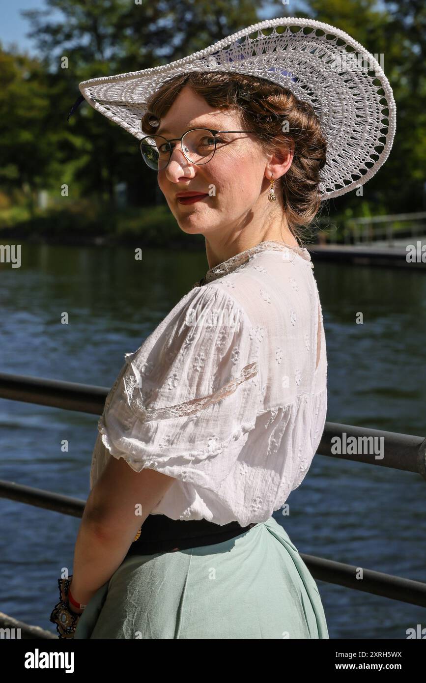 Henrichenburg, Waltrop, Germania. 10 agosto 2024. Una giovane signora in abito vittoriano vicino al canale. I fan dello steampunk, i gruppi e i visitatori, molti in costumi d'epoca retrò-futuristica o vittoriana, si divertiranno il primo giorno dell'annuale festival e mercato del Giubileo di Steampunk. Quest'anno, il festival coincide con il 125° anniversario dello storico impianto di risalita di Henrichenburg Boat Lift, sito patrimonio industriale lungo il canale Dortmund-EMS. Crediti: Imageplotter/Alamy Live News Foto Stock